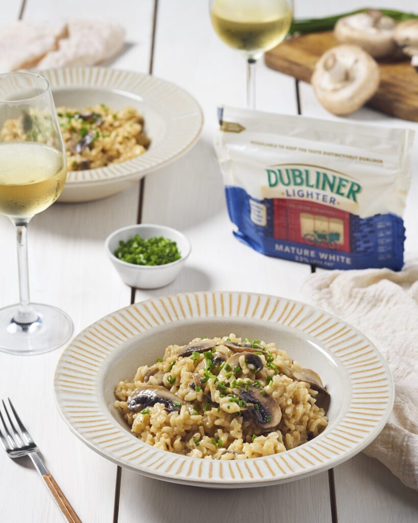 Homemade mushroom and cheese risotto on kitchen table with white wine and Dubliner Lighter white cheese